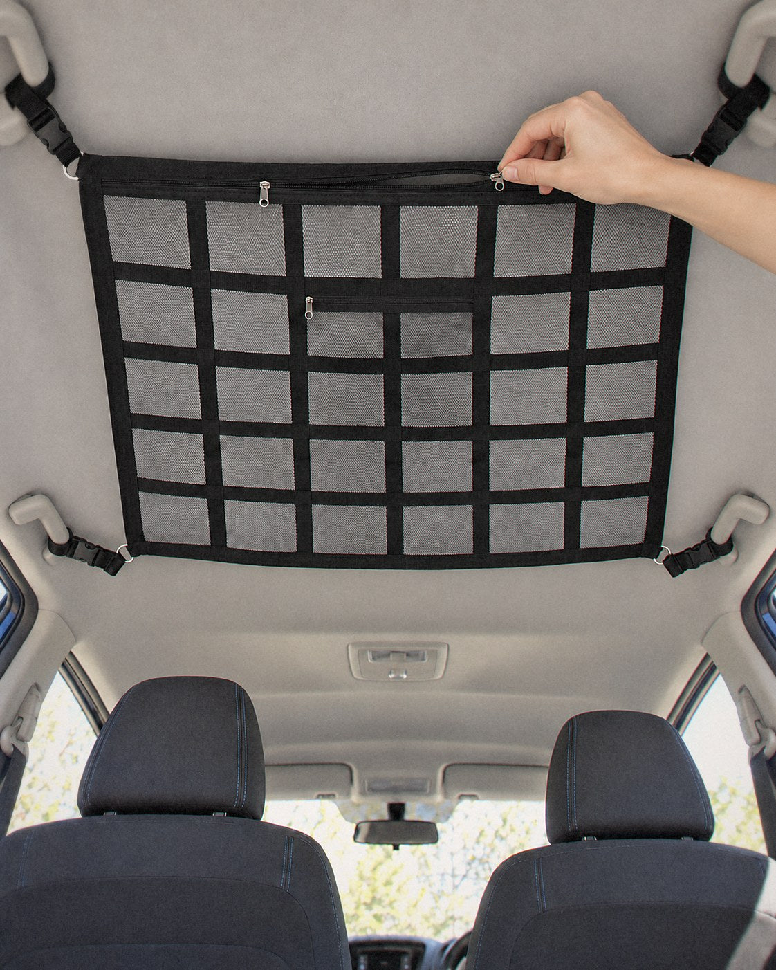 Hand unzipping an empty overhead cargo net above the front seats